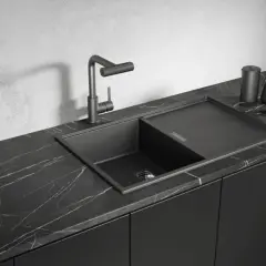 Nowoczesny, czarny zlew granitowy z baterią i ociekaczem na marmurowym blacie.